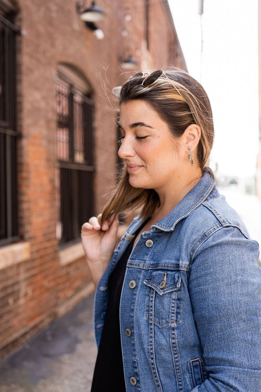 The Camy Hoops - Black Dot are medium-sized hoop earrings featuring a black and white spotted pattern, crafted from lightweight acrylics, elegantly displayed on a white rectangular dish placed on a wooden surface.