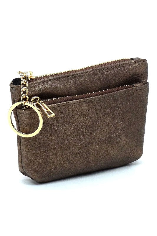 The Fashion Keychain Coin Purse is a compact, textured brown coin holder made from vegan leather. It features a zippered closure, an external pocket, and comes with an attached gold keyring.