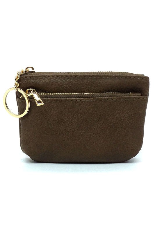 The Fashion Keychain Coin Purse is a compact, textured brown coin holder made from vegan leather. It features a zippered closure, an external pocket, and comes with an attached gold keyring.