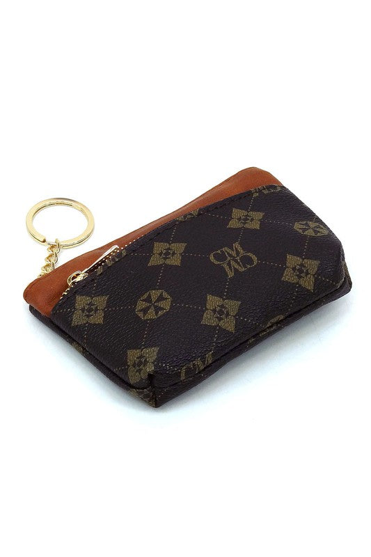 The CM Monogram Keychain Coin Purse is a small, white faux vegan leather pouch adorned with a brown geometric pattern. It features a brown zipper and comes with a gold CM Monogram keychain, along with the letters "CMWD".