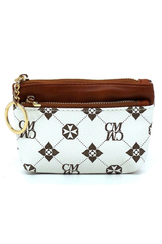 The CM Monogram Keychain Coin Purse is a small, white faux vegan leather pouch adorned with a brown geometric pattern. It features a brown zipper and comes with a gold CM Monogram keychain, along with the letters "CMWD".