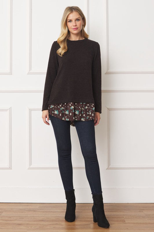 A woman wearing the Layered Floral Tulip Hem Back Accent Top, a long-sleeve black top with a layered floral hem, and dark blue jeans is shown from the front and back.