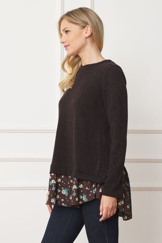 A woman wearing the Layered Floral Tulip Hem Back Accent Top, a long-sleeve black top with a layered floral hem, and dark blue jeans is shown from the front and back.