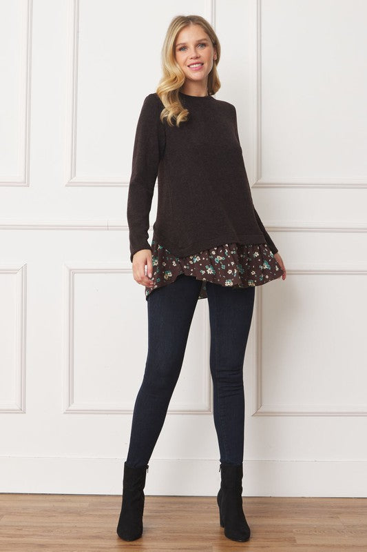 A woman wearing the Layered Floral Tulip Hem Back Accent Top, a long-sleeve black top with a layered floral hem, and dark blue jeans is shown from the front and back.