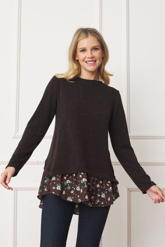A woman wearing the Layered Floral Tulip Hem Back Accent Top, a long-sleeve black top with a layered floral hem, and dark blue jeans is shown from the front and back.
