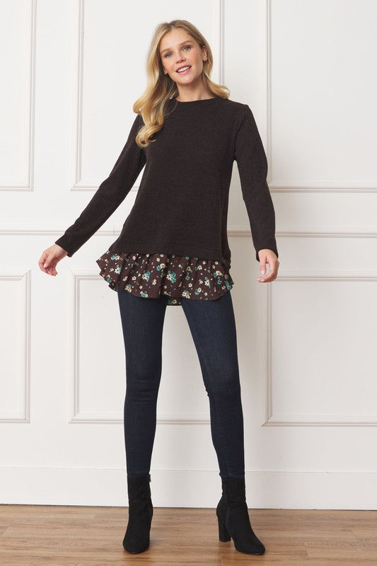 A woman wearing the Layered Floral Tulip Hem Back Accent Top, a long-sleeve black top with a layered floral hem, and dark blue jeans is shown from the front and back.