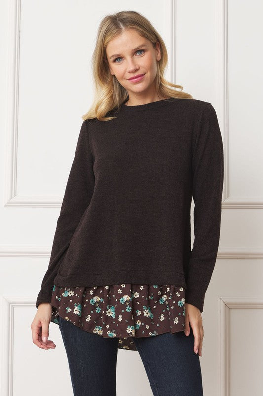 A woman wearing the Layered Floral Tulip Hem Back Accent Top, a long-sleeve black top with a layered floral hem, and dark blue jeans is shown from the front and back.