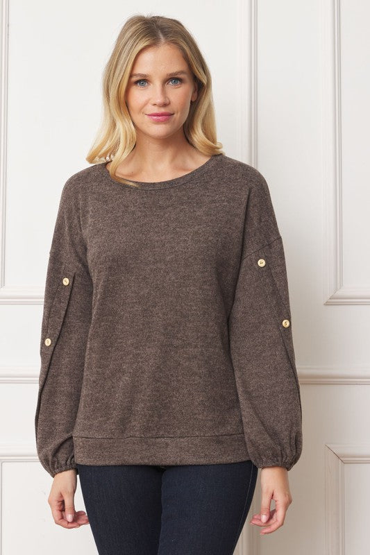 A woman is standing and smiling, wearing the Drop Shoulder Button Sleeve Detail Top in brown and dark pants.