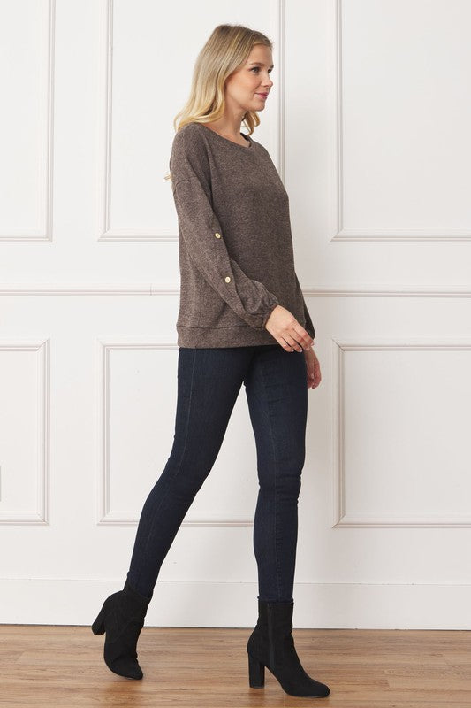A woman is standing and smiling, wearing the Drop Shoulder Button Sleeve Detail Top in brown and dark pants.