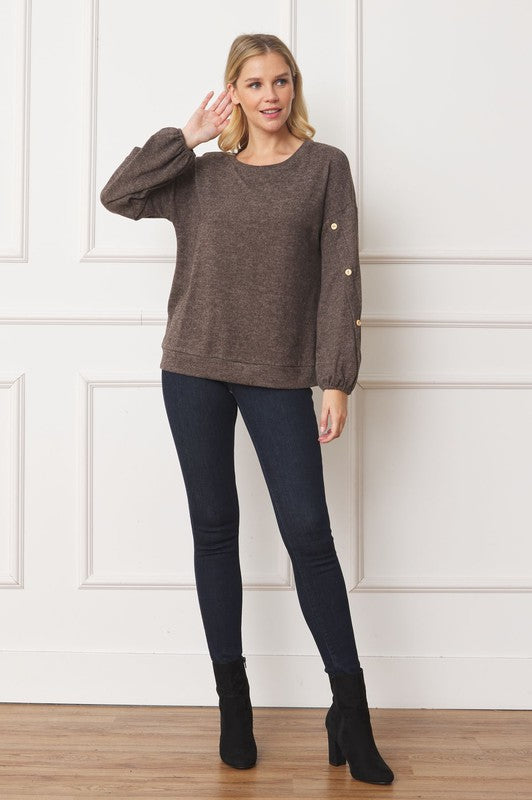 A woman is standing and smiling, wearing the Drop Shoulder Button Sleeve Detail Top in brown and dark pants.