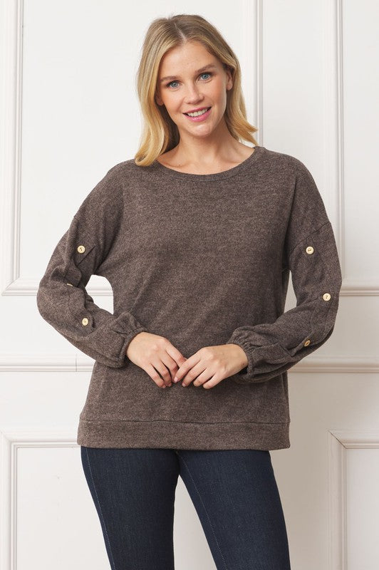 A woman is standing and smiling, wearing the Drop Shoulder Button Sleeve Detail Top in brown and dark pants.