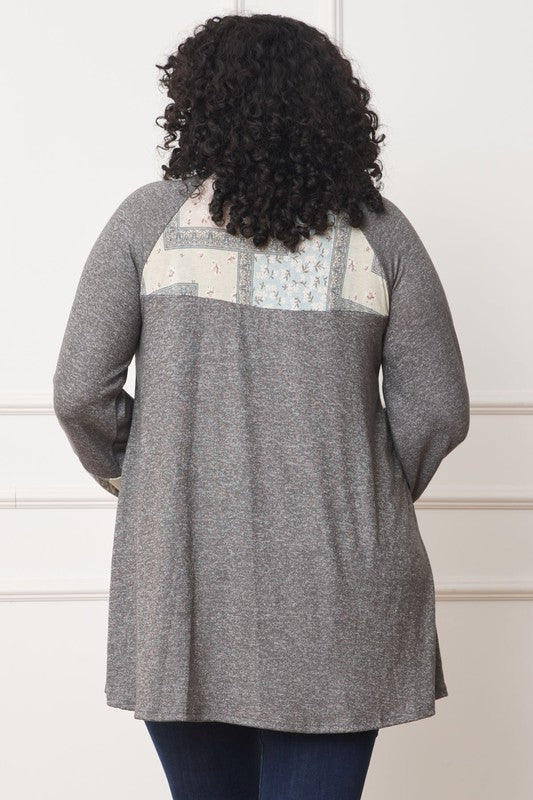 A person with curly hair is wearing a long-sleeved brown Plus Patchwork Panel Accent A-Line Tunic, standing in front of a white wall.