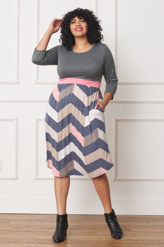 A woman with curly hair smiles, adorning a Plus Curved Hem Band Midi Dress made from a polyester and spandex blend. The black dress showcases three-quarter sleeves and is accented with a red waistband. The skirt is decorated with an eye-catching floral pattern of large pink and orange flowers.