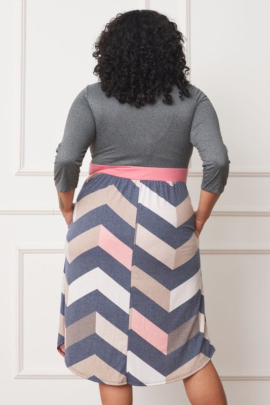 A woman with curly hair smiles, adorning a Plus Curved Hem Band Midi Dress made from a polyester and spandex blend. The black dress showcases three-quarter sleeves and is accented with a red waistband. The skirt is decorated with an eye-catching floral pattern of large pink and orange flowers.