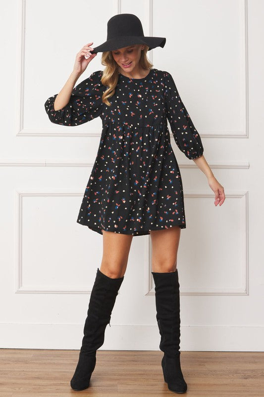 A person in a Plus Abstract Polka Dot Bishop Sleeve Mini Dress and a black hat stands smiling against a white background.