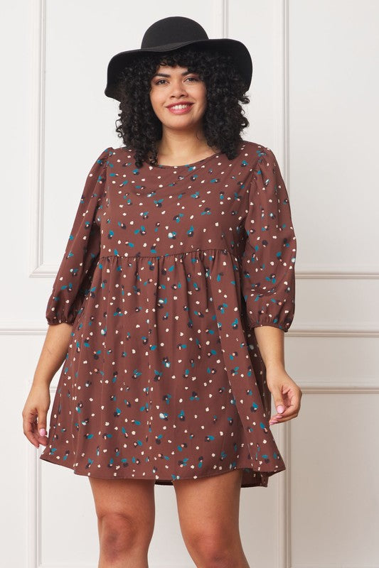 A woman with curly hair in a black hat wears the Plus Abstract Polka Dot Bishop Sleeve Mini Dress, standing against a white wall background.