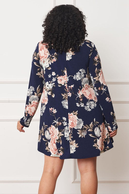 A person with curly hair smiles while wearing a Floral Chiffon Layered Mini Dress with long sleeves and a high-low hemline, standing against a neutral background.