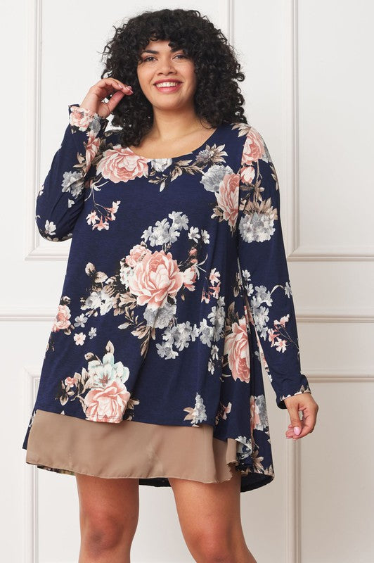 A person with curly hair smiles while wearing a Floral Chiffon Layered Mini Dress with long sleeves and a high-low hemline, standing against a neutral background.
