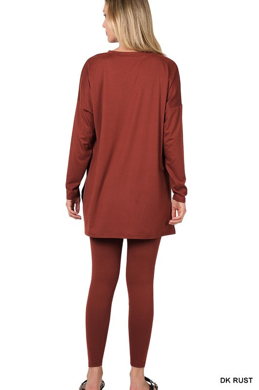 Clad in the Brushed DTY Microfiber Loungewear Set, a person stands against a plain background, showcasing its buttery soft, bright pink long-sleeve top and matching leggings, complemented by white sneakers.