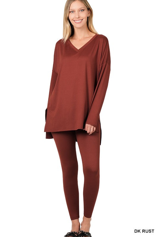 Clad in the Brushed DTY Microfiber Loungewear Set, a person stands against a plain background, showcasing its buttery soft, bright pink long-sleeve top and matching leggings, complemented by white sneakers.