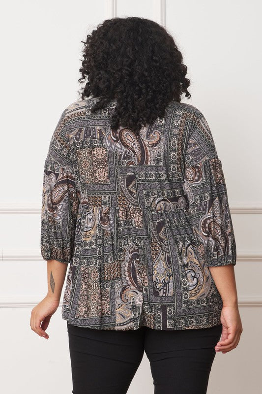 A person with curly hair is shown from the back, wearing a Plus Button Accent Paisley Top, featuring a stylish gray and black pattern with mid-length sleeves.