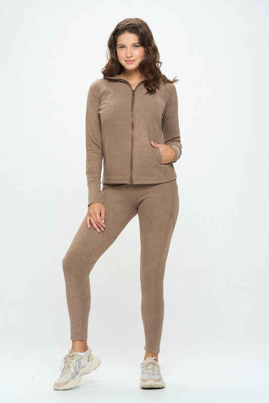 A person stands against a plain background wearing the Basic Fall Casual set 8987, which includes a light brown zip-up jacket and matching leggings made from stretch fabric. With one hand in the jacket pocket and the other resting by their side, this outfit is perfect for casual fall days.