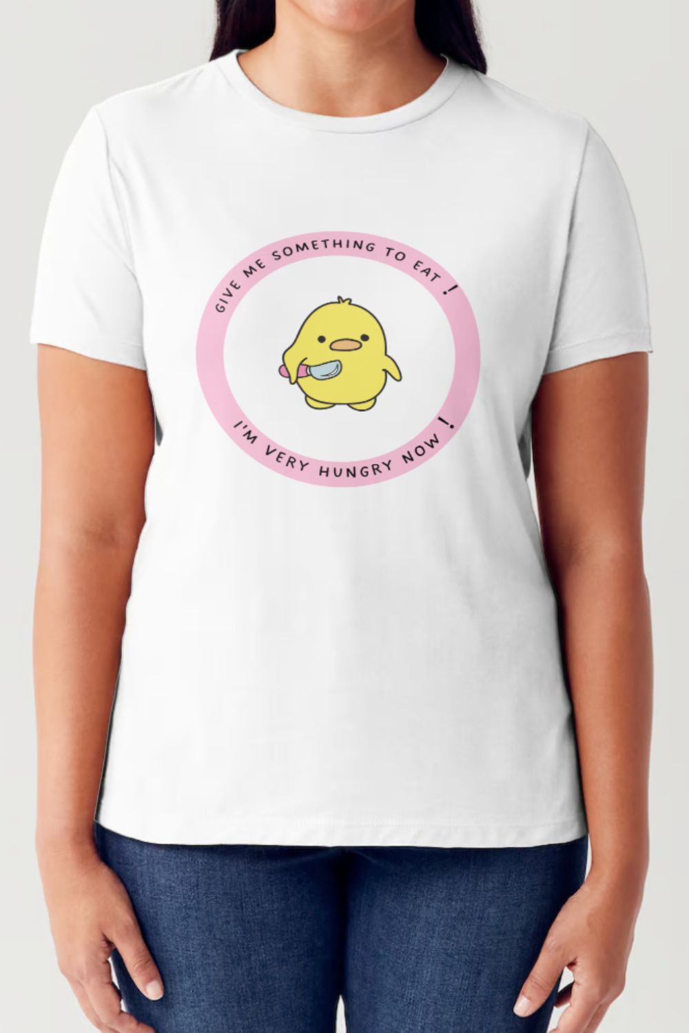 A person wearing the Simply Love Full Size Cute Graphic Short Sleeve Tubular T-Shirt, made of ringspun combed cotton and featuring a cartoon yellow bird in the center holding a fork and knife, surrounded by the text "Give me something to eat! I'm very hungry now!" in a pink circle. It's an ideal piece for any casual wardrobe.