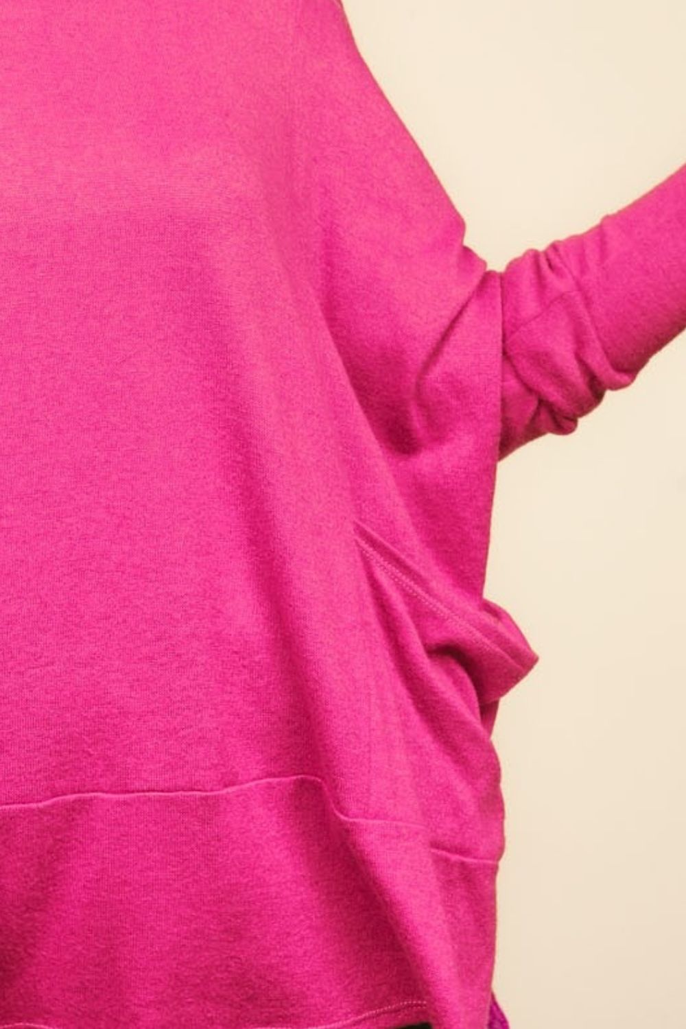 A person wearing a Haptics Dolman Long Sleeve Oversized Knit Top with Pockets in bright pink stands against a plain background.