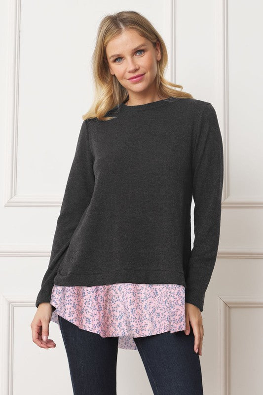 A woman wearing the Layered Floral Tulip Hem Back Accent Top, a long-sleeve black top with a layered floral hem, and dark blue jeans is shown from the front and back.