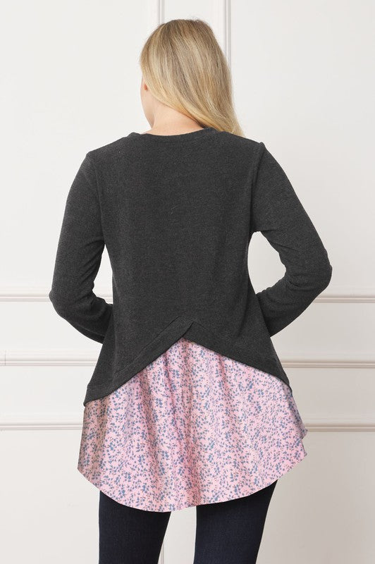A woman wearing the Layered Floral Tulip Hem Back Accent Top, a long-sleeve black top with a layered floral hem, and dark blue jeans is shown from the front and back.