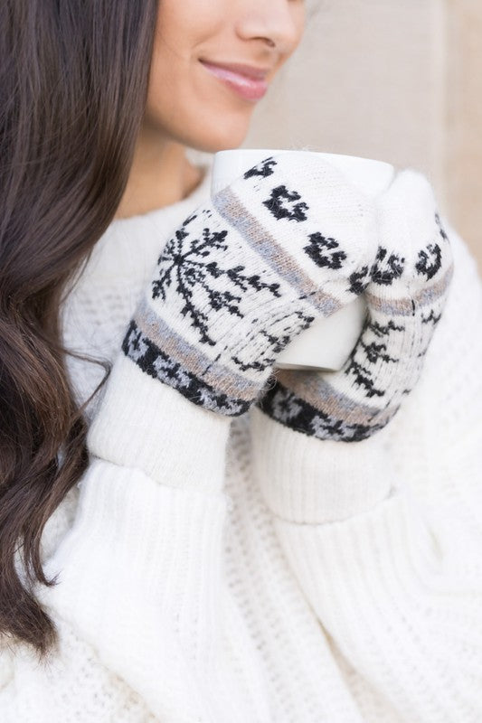 Woman smiling with her eyes closed, wearing the Nordic Snowflake Mittens and a white sweater.