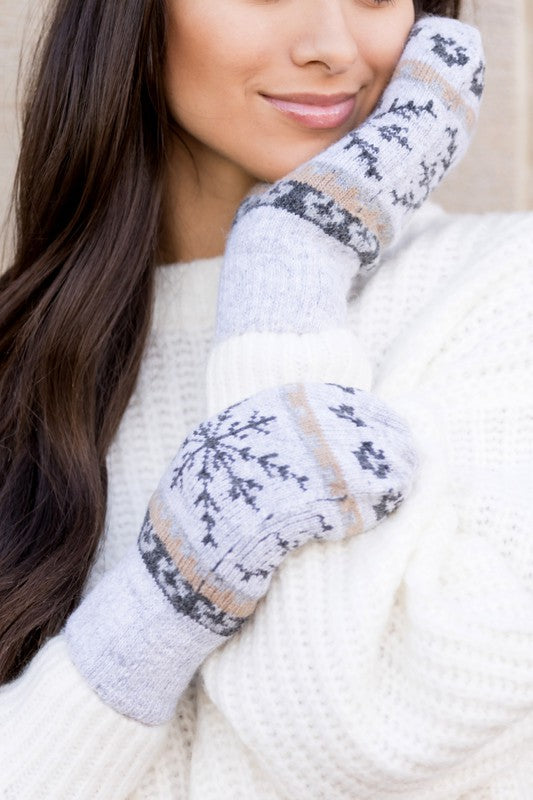 Woman smiling with her eyes closed, wearing the Nordic Snowflake Mittens and a white sweater.