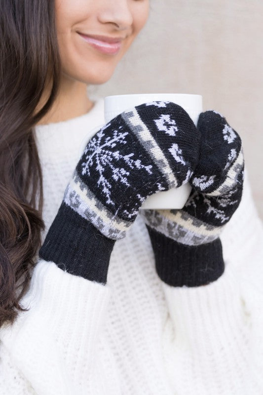 Woman smiling with her eyes closed, wearing the Nordic Snowflake Mittens and a white sweater.