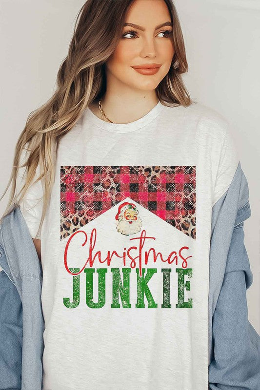 A woman wearing a CHRISTMAS JUNKIE GRAPHIC TEE / T-SHIRT that features a Santa graphic and animal print designs smiles at the camera.