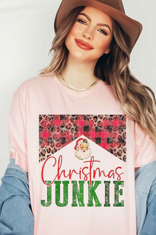 A woman wearing a CHRISTMAS JUNKIE GRAPHIC TEE / T-SHIRT that features a Santa graphic and animal print designs smiles at the camera.