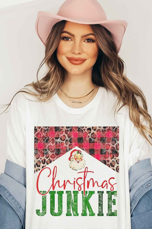 A woman wearing a CHRISTMAS JUNKIE GRAPHIC TEE / T-SHIRT that features a Santa graphic and animal print designs smiles at the camera.