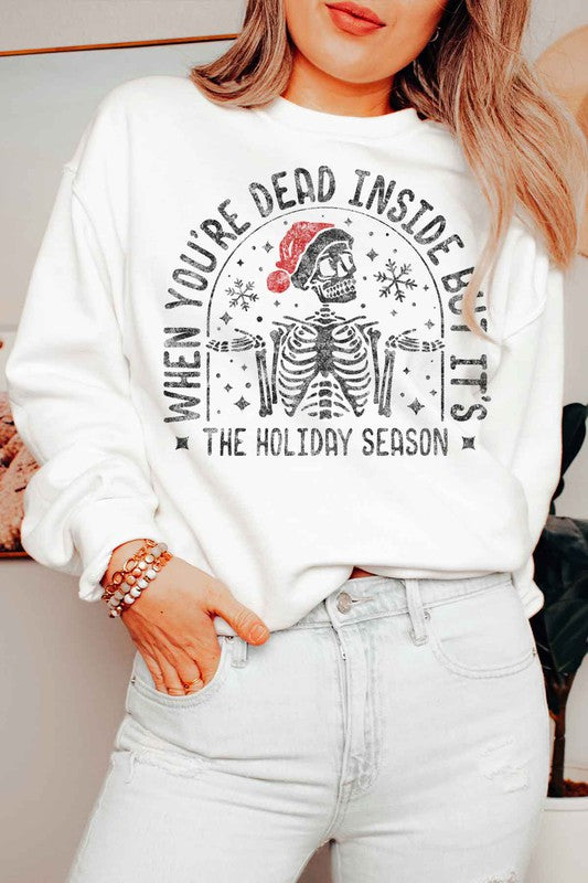 Person wearing the Christmas Skeleton Graphic Sweatshirt in premium cotton gray, which features a festive skeleton with a Santa hat and the text "When you’re dead inside, but it’s the holiday season." A perfect addition to your holiday wardrobe.