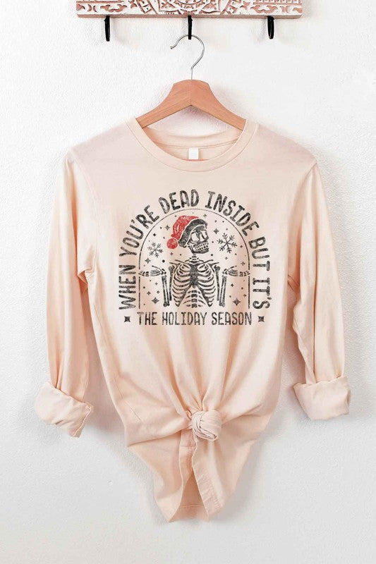 A CHRISTMAS SKELETON LONG SLEEVE TEE on a hanger, showcasing a premium cotton fabric with a Christmas skeleton in a Santa hat and the text "WHEN YOU'RE DEAD INSIDE BUT IT'S THE HOLIDAY SEASON".