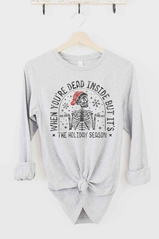 A CHRISTMAS SKELETON LONG SLEEVE TEE on a hanger, showcasing a premium cotton fabric with a Christmas skeleton in a Santa hat and the text "WHEN YOU'RE DEAD INSIDE BUT IT'S THE HOLIDAY SEASON".