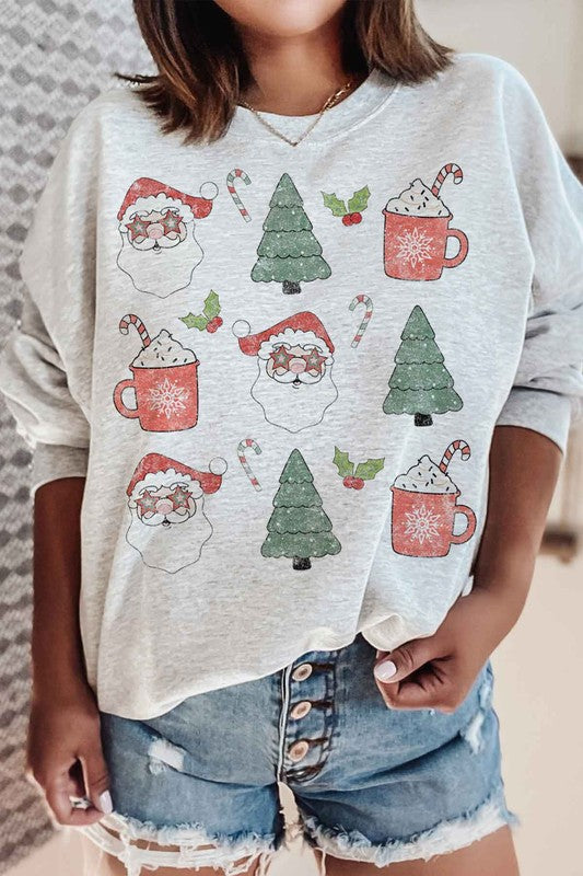 Person wearing the CHRISTMAS COLLECTION GRAPHIC SWEATSHIRT in light gray, featuring festive prints of Santa faces, hot cocoa mugs, Christmas trees, and candy canes, paired with denim shorts.