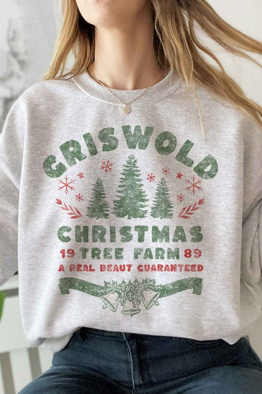 Person wearing a cozy CHRISTMAS TREE FARM GRAPHIC PLUS SIZE SWEATSHIRT in white, adorned with green and red text: "Griswold Christmas Tree Farm '89, A Real Beaut Guaranteed," showcasing festive Christmas trees and holiday decorations. Perfect for a charming visit to the Christmas tree farm!