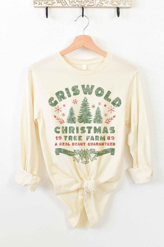 A premium cotton CHRISTMAS TREE FARM LONG SLEEVE TEE in cream hangs on a wooden hanger. It features green and red text and graphics promoting "Griswold Christmas Tree Farm" with a festive design of trees and snowflakes.