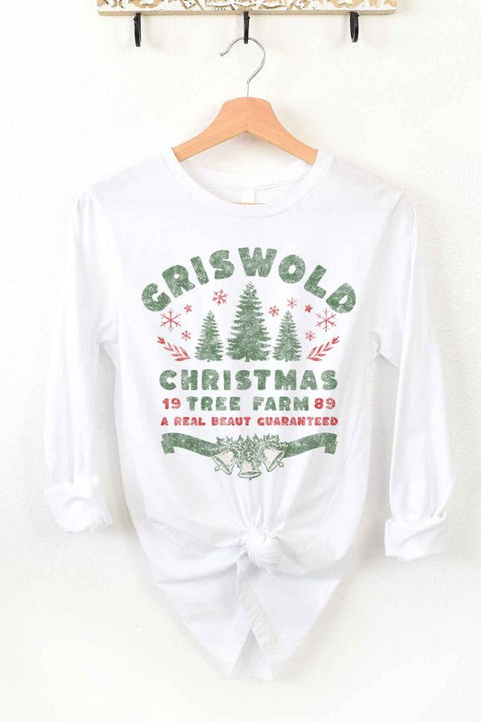 A premium cotton CHRISTMAS TREE FARM LONG SLEEVE TEE in cream hangs on a wooden hanger. It features green and red text and graphics promoting "Griswold Christmas Tree Farm" with a festive design of trees and snowflakes.