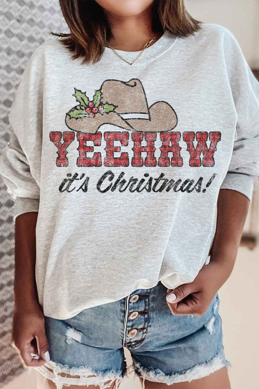 Individual dressed in a YEEHAW COUNTRY CHRISTMAS PLUS SIZE SWEATSHIRT, featuring a cowboy hat and holly graphic, along with the phrase "YEEHAW it's Christmas!" written on it.