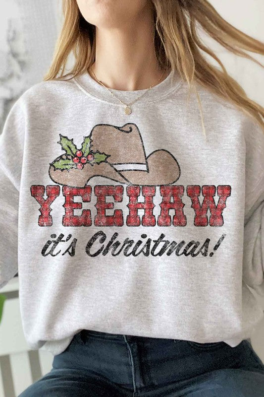 Individual dressed in a YEEHAW COUNTRY CHRISTMAS PLUS SIZE SWEATSHIRT, featuring a cowboy hat and holly graphic, along with the phrase "YEEHAW it's Christmas!" written on it.