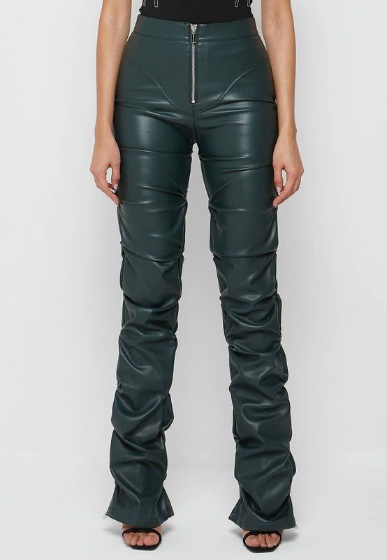 A woman stands against a plain background, wearing a black sleeveless top and high-waisted SEXY PU LEATHER PANTS in dark green. The pants are made from polyester fabric. She holds a small black handbag and has long, straight hair.