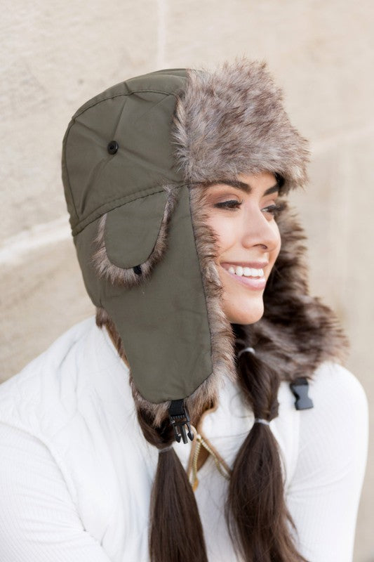 A woman smiling while adjusting a whimsical animal-themed Alpine Aviator Trapper hat.