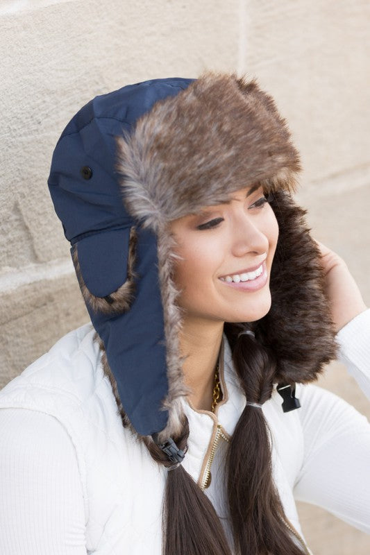 A woman smiling while adjusting a whimsical animal-themed Alpine Aviator Trapper hat.