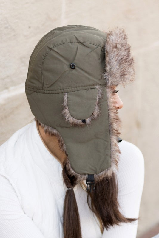 A woman smiling while adjusting a whimsical animal-themed Alpine Aviator Trapper hat.