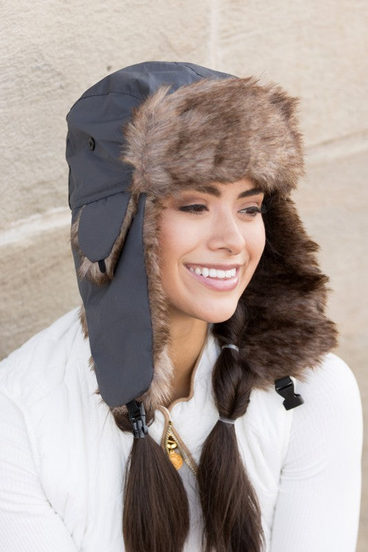 A woman smiling while adjusting a whimsical animal-themed Alpine Aviator Trapper hat.